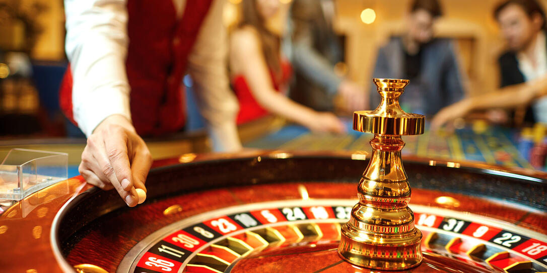 The croupier holds a roulette ball in a casino in his hand.