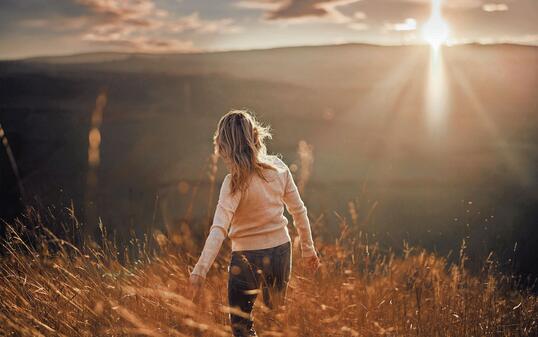 Back view of carefree woman in autumn day on a hill at sunset.