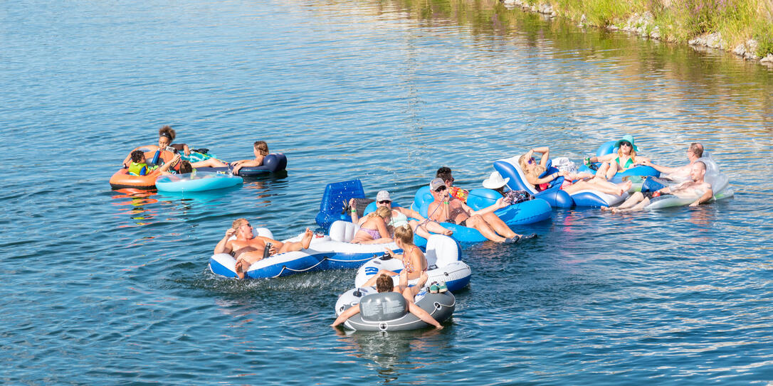 Large group of people floating down the Penticton River Channel in summer