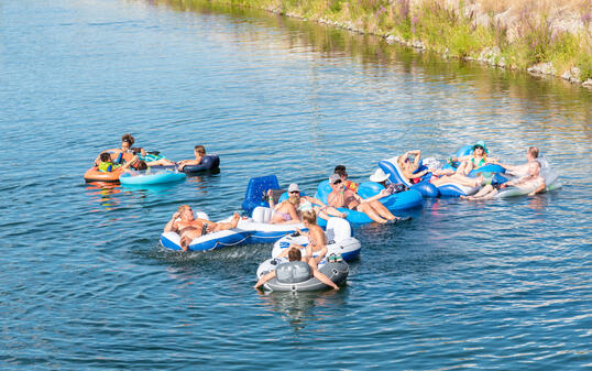 Large group of people floating down the Penticton River Channel in summer