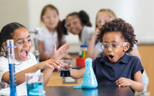 Excited students doing chemistry experiement in science class at school