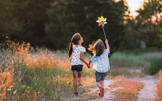 Happy Kids having fun with pinwheel in the nature. Running kids