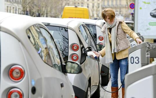 Woman charging Electric Car on Paris Street