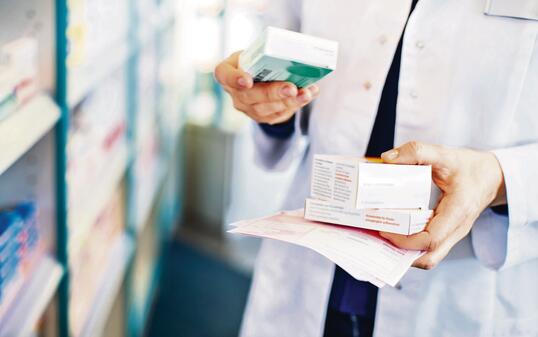 Pharmacist's hands taking medicines from shelf