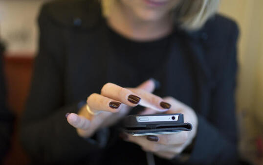 Eine Frau twittert in einem SBB-Zug via Smartphone (Archiv)