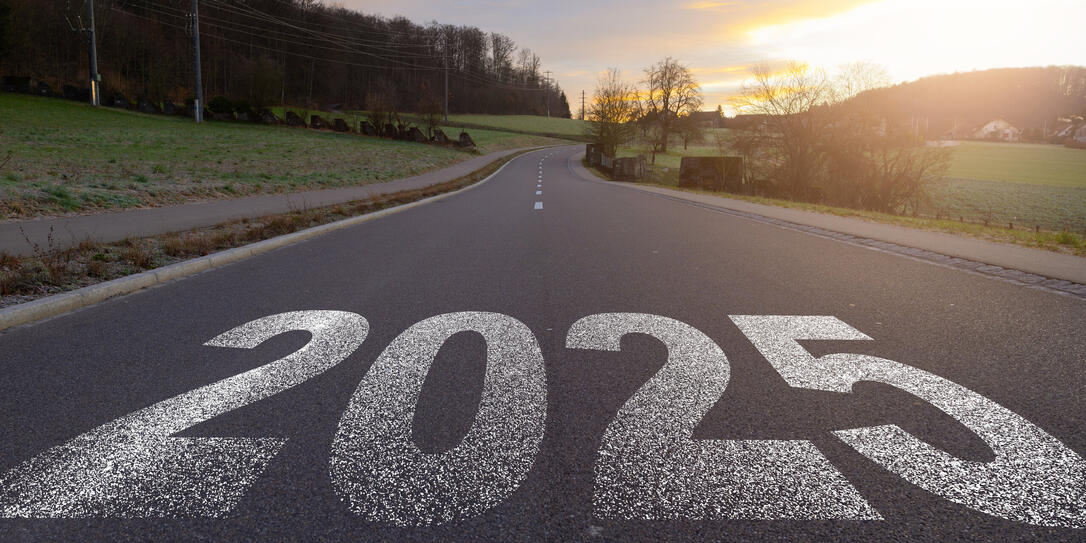 The word 2025 written on highway road in the middle of empty asphalt road at golden sunset and beautiful blue sky. Concept for year 2025.