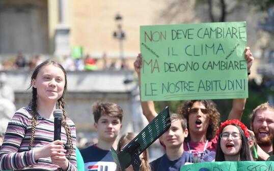 "Nicht das Klima muss sich ändern, aber unsere Gewohnheiten müssen es", halten Klima-Aktivisten in Rom in die Höhe, angeführt von der 16-jährigen Schwedin Greta Thunberg (links, mit Mikrophon).