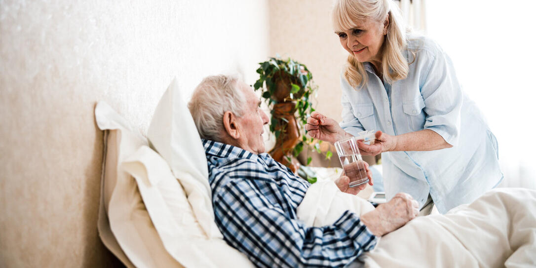 Wife giving pills and water to her husband