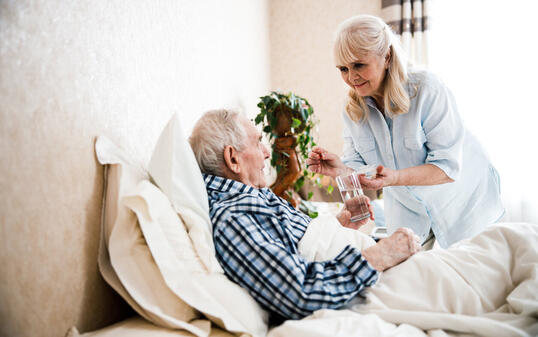 Wife giving pills and water to her husband