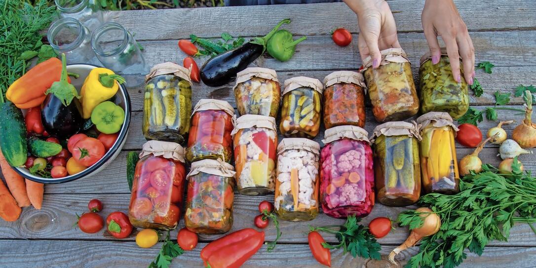 Woman canning vegetables in jars on the background of nature. preparations for the winter