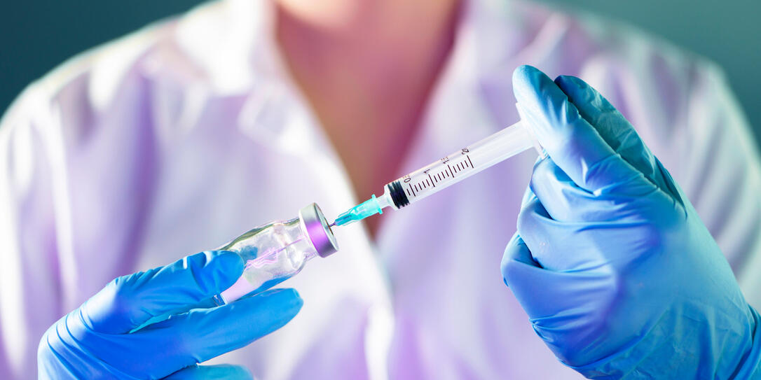 female Doctor hand holding syringe and covid-19 vaccine in blue gloves with white coat. Disease injection concept.