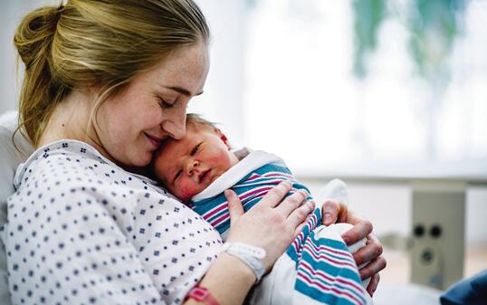 New mom holds her baby in hospital bed