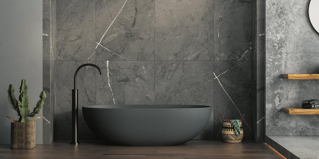 A modern bathroom featuring an anthracite bathtub, marble ceramic tiles on the back wall, parquet flooring, plants and a basket. 3d rendering