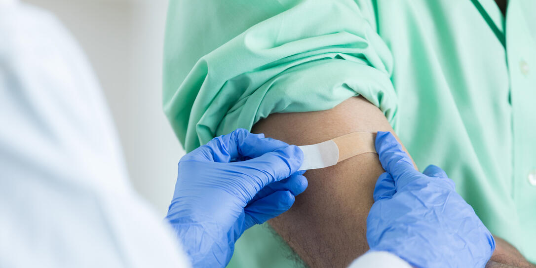 Closeup of unrecognizable pharmacist placing bandaid on customer's arm