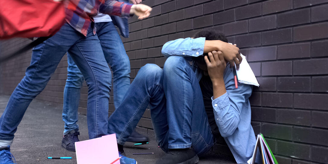 Cruel teenagers scattering classbooks of afro-american boy, school bullying