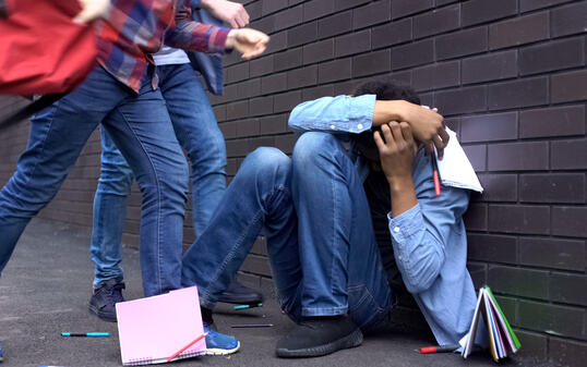 Cruel teenagers scattering classbooks of afro-american boy, school bullying