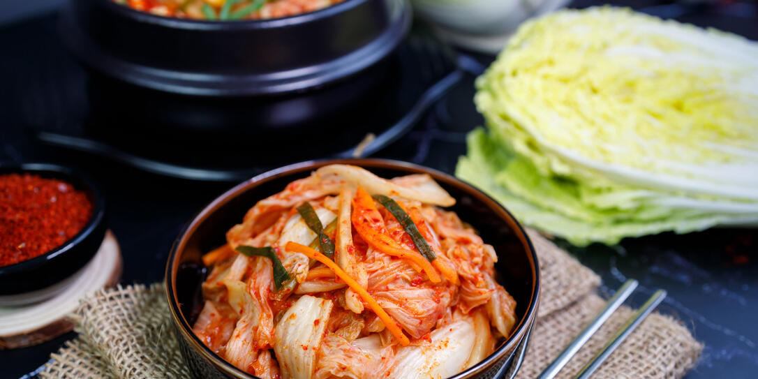 Eating kimchi cabbage and rice in a black bowl with chopsticks, Korean food.