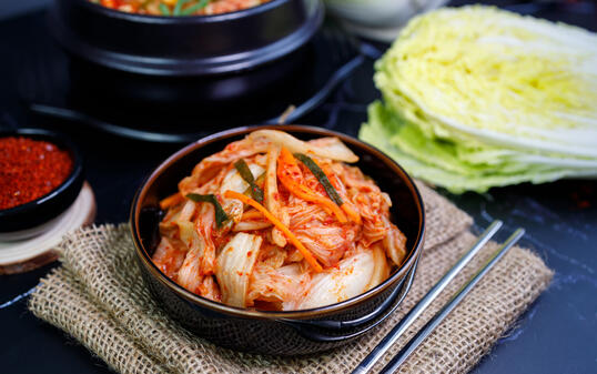 Eating kimchi cabbage and rice in a black bowl with chopsticks, Korean food.