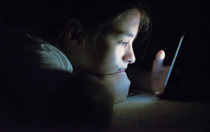 Teenager sending email from smart phone in her bed