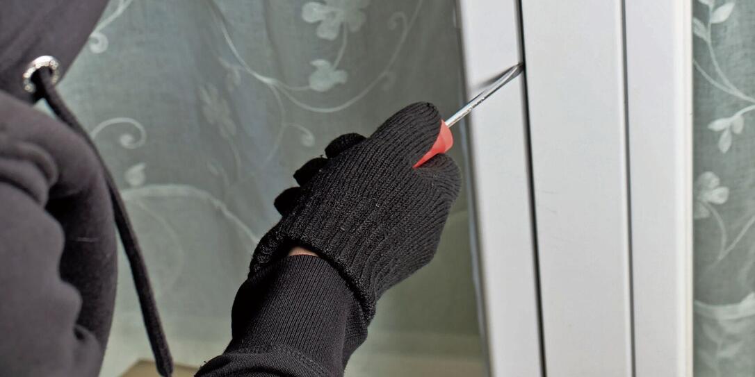 Thief with screwdriver violating terrace door to access the interior of housing