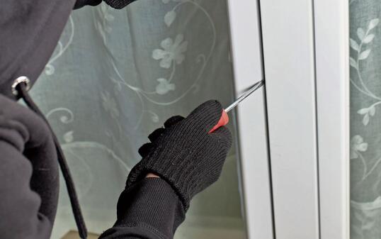 Thief with screwdriver violating terrace door to access the interior of housing