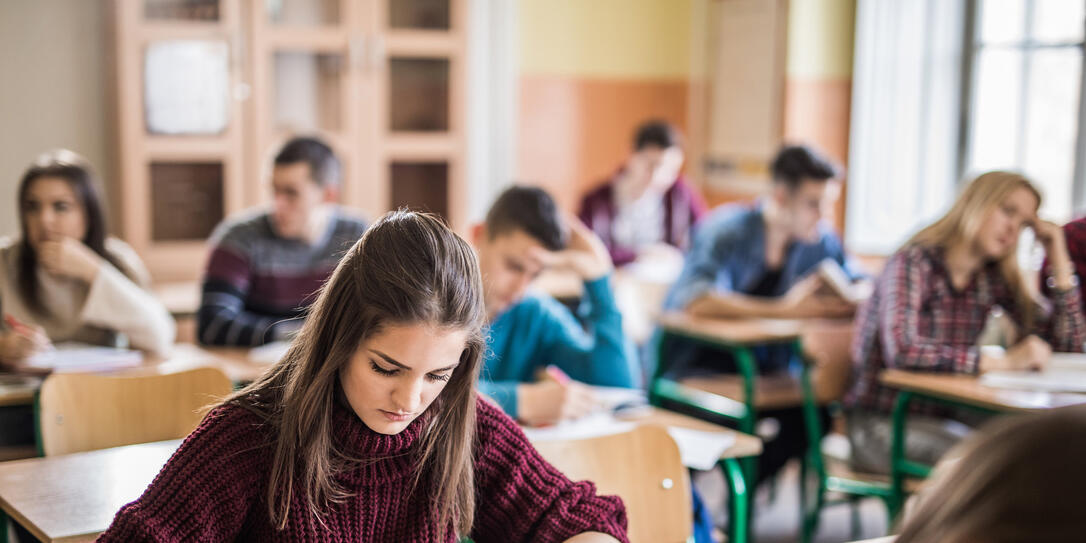 Female high school student writing a test in the classroom.