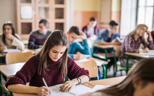 Female high school student writing a test in the classroom.