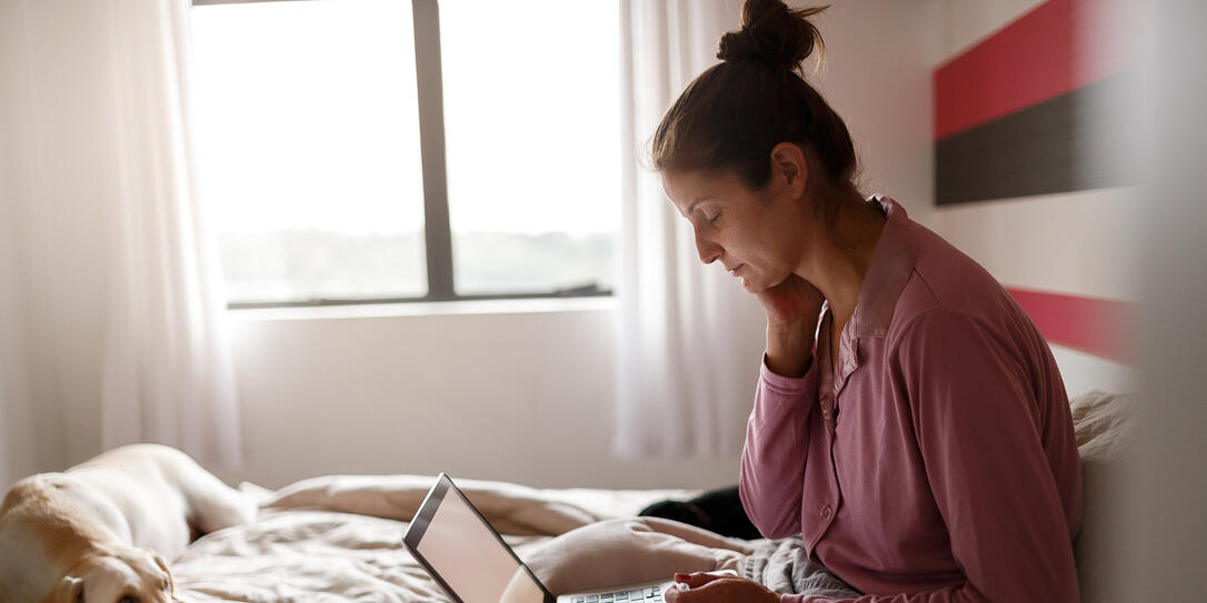 Sick woman on bed video chatting with doctor on laptop